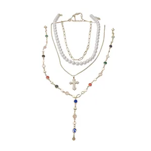 Multi-layered pearl and chain necklace with rhinestone cross and colorful Y-shaped drop.