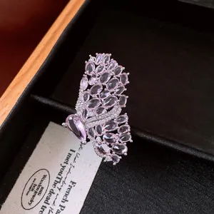 Detailed close-up of a luxury vintage pink butterfly ring with micro-paved stones on black velvet.