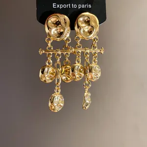 Close-up of elegant golden hammered metal drop earrings with vintage pleated texture details