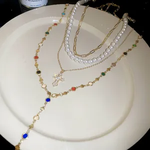 Detailed view of multi-layer necklace with pearls, cross pendant and colorful beads
