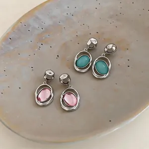 Detailed view of minimalist French style oval acrylic drop earrings in teal and pink colors.