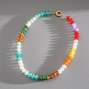 Close-up of vibrant multi-color beads and a gold-toned spring ring clasp on grey surface