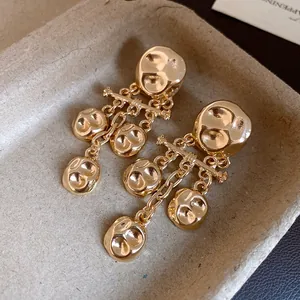 Close-up of gold-tone wrinkled metal drop earrings with vintage hammered texture