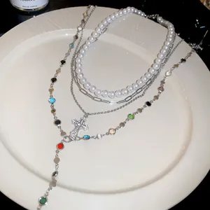 Detail of multi-layer necklace with resin pearls, colorful stones, and a cross pendant