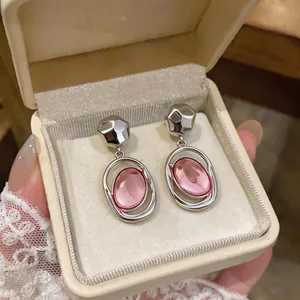 Close-up of French minimalist silver earrings with oval pink acrylic pendants in a box
