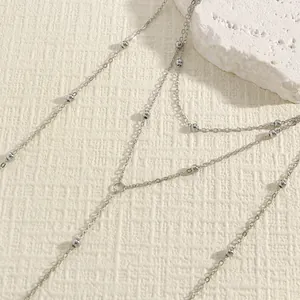 Detailed macro view of a silver double-layered body chain with small round beads.