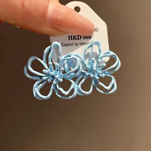 Pendientes de flores huecas azul claro con esmalte y diseño de aguja plata