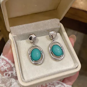 Macro view of French minimalist oval turquoise drop earrings displayed in a gift box