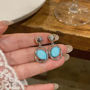 Detailed close-up of French minimalist oval turquoise drop earrings with silver finish.