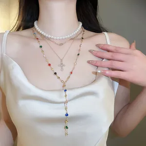 Close-up of a layered Y-shaped necklace with pearls, cross pendant, and colorful beads.