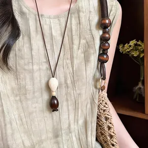 Detail view of a bohemian wooden seed pendant necklace on a minimalist brown cord.