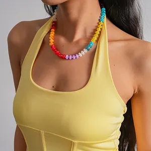 Close-up detail of a colorful acrylic beaded choker necklace on a model wearing yellow.