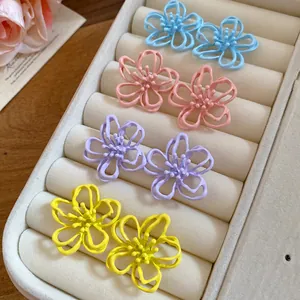 Primer plano de pendientes de flores huecas de colores en un joyero beige