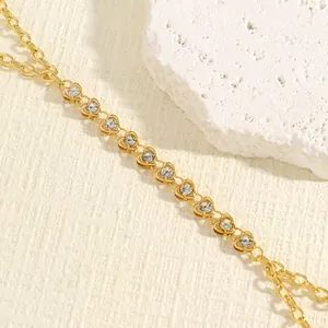 Detailed view of elegant golden heart-shaped rhinestone body chain on white textured stone