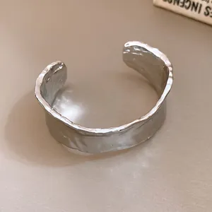 Primer plano de un brazalete plateado minimalista con una textura arrugada única
