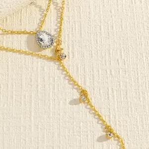 Close-up detail of golden body chain with pear-shaped crystal and small rhinestone drops