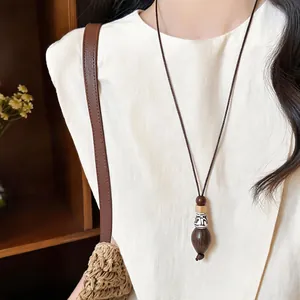 Close-up view of bohemian ethnic necklace with a wooden pendant worn by a model.