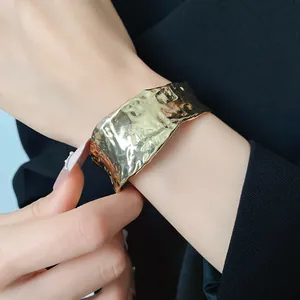 Vista detallada de brazalete dorado con textura martillada y diseño arrugado
