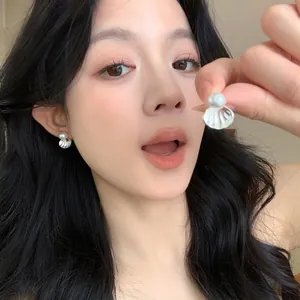 Close-up detail of French style elegant pearl shell stud earrings worn by an Asian model