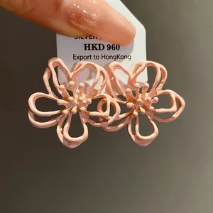 Detalle de pendientes de flor hueca rosa con elegante acabado en aceite.