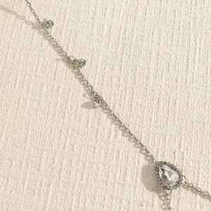 Close-up detail of a vintage-style silver body chain featuring sparkling teardrop crystals