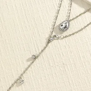 Close-up detail of a double-layer silver body chain featuring a water-drop crystal pendant.