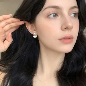 Close-up of elegant pearl and shell-textured drop earring worn by a model for detail view