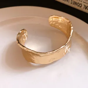 Vista detallada de un brazalete dorado con una textura de metal arrugado artístico