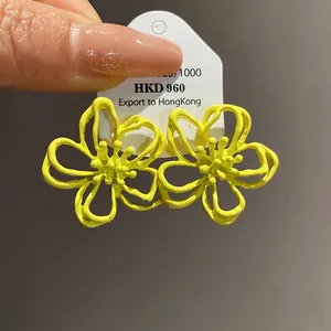 Vista macro detallada de pendientes de botón de flor hueca amarilla de plata 925