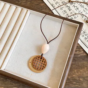 Detail of a bohemian woven pendant necklace with a round brown lattice and bead.