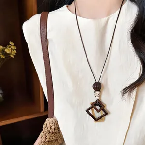 Detail showing a bohemian geometric square pendant on a long cord necklace.