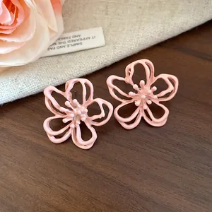 Primer plano de pendientes de flor rosa calada con un diseño dulce y elegante.