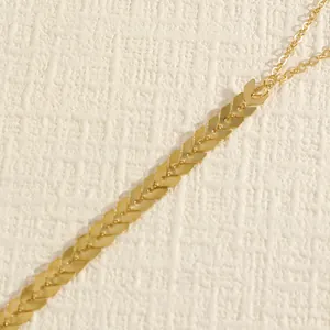 Close-up detail of a vintage gold-tone arrow-link body chain on a textured background.