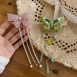 Vue détaillée de la broderie complexe et des élégants glands en perles sur les barrettes papillon