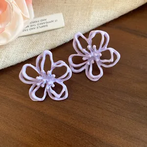 Detalle de cerca de los pendientes de botón de flores caladas moradas con un acabado mate