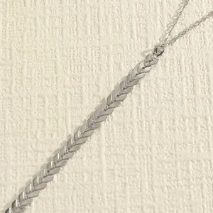 Detailed macro shot of a silver vintage body chain with elegant chevron link pattern.