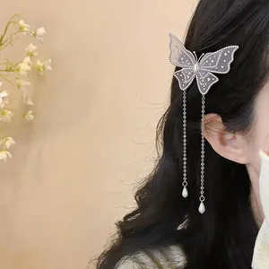 Détail d'une élégante pince à cheveux papillon brodée avec des glands de perles sur cheveux