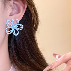 Detalle en primer plano de pendientes de botón de flor hueca azul claro esmaltados