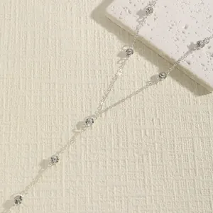 Detail view of retro silver double-layer body chain with delicate beads on textured background.