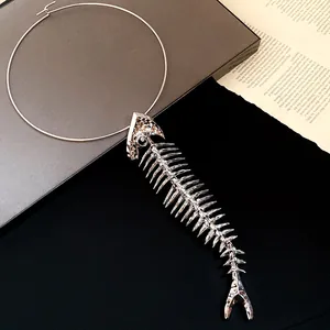 Close-up detail of silver metallic fishbone pendant on a minimalist neck ring