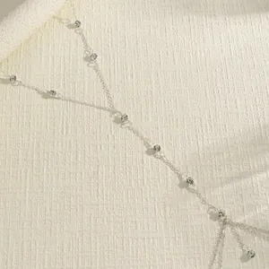 Close-up detail of a delicate silver double-layer body chain with sparkling beads.