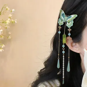 Vue détaillée d'une pince à cheveux papillon brodée verte avec d'élégants longs glands