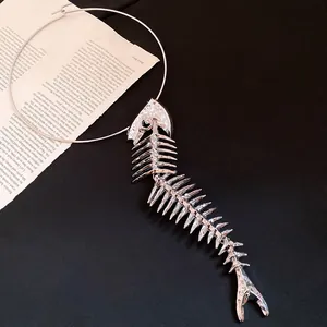 Close-up detail of a large silver metallic fishbone pendant on a minimalist choker ring