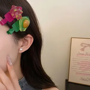 Barrettes à cheveux en résine avec motifs avocat et fruit du dragon sur modèle.