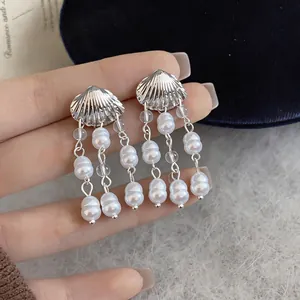 Vue détaillée de boucles d'oreilles coquillage en argent avec glands de perles blanches