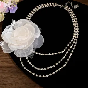 Detail of elegant multi-layer rhinestone choker featuring a large white chiffon flower