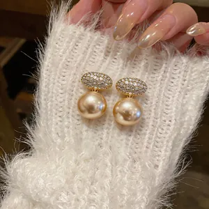 Close-up of French style zircon oval gold pearl clip-on earrings on fuzzy white knit