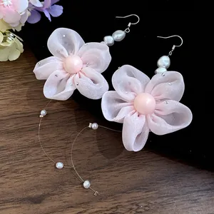 Close-up view of elegant pink chiffon flower earrings featuring pearls and long tassels.