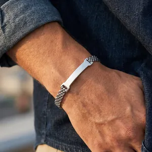 Close-up detail of a stainless steel mesh bracelet featuring a polished curved plate