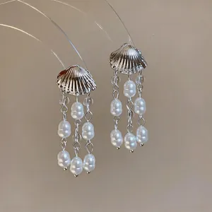 Vue détaillée d'élégantes boucles d'oreilles en forme de coquillage et glands de perles